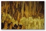 Salle des Concrétions et Lac Noir. Les formations illuminées se détachent sur le fond sombre de la grotte.